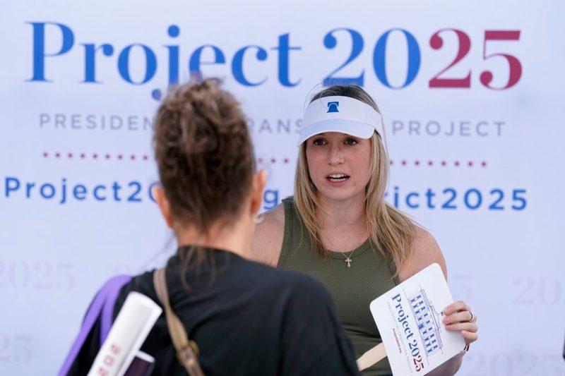 Kristen Eichamer, right, talks to a fairgoer at the Project 2025 tent at the Iowa State Fair, Aug. 14, 2023, in Des Moines, Iowa. With more than a year to go before the 2024 election, a constellation of conservative organizations is preparing for a possible second White House term for Donald Trump. The Project 2025 effort is being led by the Heritage Foundation think tank. (AP Photo/Charlie Neibergall)