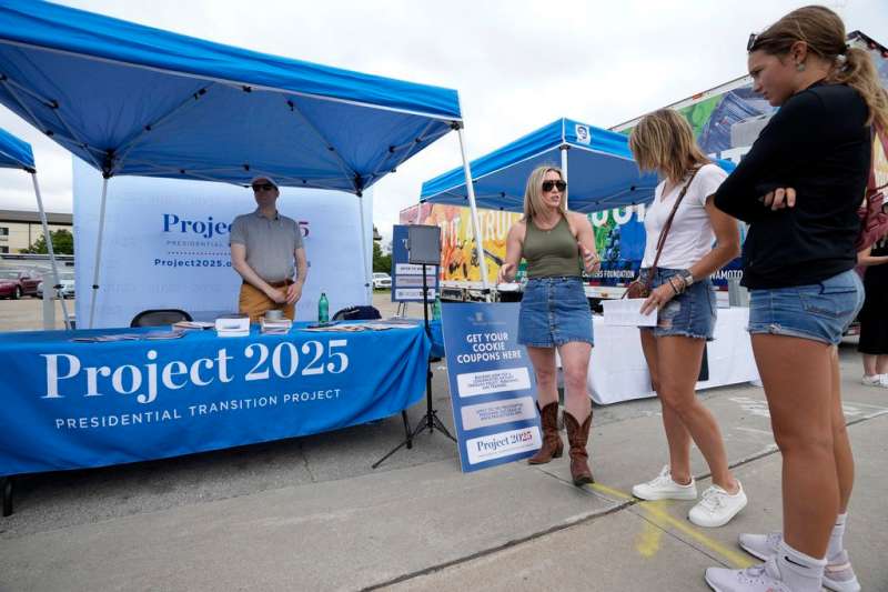 Kristen Eichamer, center, talks to fairgoers in the Project 2025 tent at the Iowa State Fair, Aug. 14, 2023, in Des Moines, Iowa. With more than a year to go before the 2024 election, a constellation of conservative organizations is preparing for a possible second White House term for Donald Trump. The Project 2025 effort is being led by the Heritage Foundation think tank. (AP Photo/Charlie Neibergall)