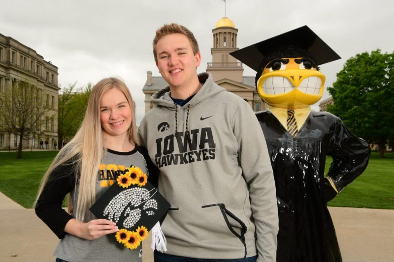 Two young Iowa students standing with the college's mascot.