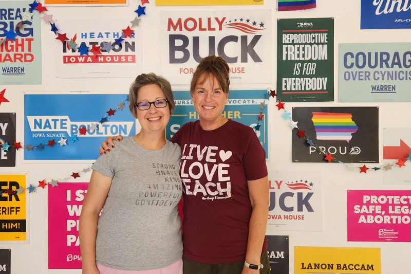 Reps. Heather Matson and Molly Buck pose together in front of a wall covered in campaign posters before going out door knocking to ask people about their issues. Both said they've heard many people say Iowa's near-total abortion ban is why they're voting for Democrats this year.