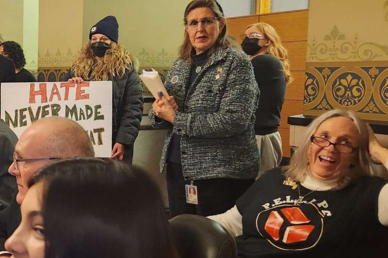 Sen. Sandy Salmon at the subcommittee to potentially expose drag performances to obscentiy lawsuits. A protester to her left has a sign that says "Hate never made America great."