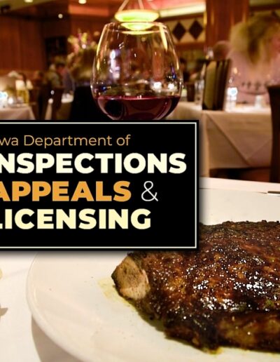 a white plate with a steak next to a white plate with bread and butter with a glass of red wine in the background