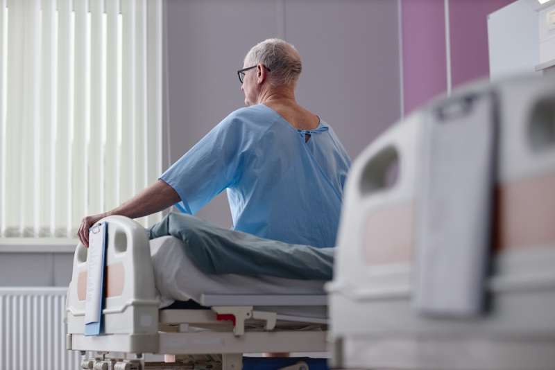 Photo of a man sitting up in a hospital bed.